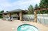 Inviting outdoor lounge with a pergola, stone pillars, and a bubbling hot tub.