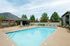 Inviting outdoor pool surrounded by a lounge area, set against a backdrop of trees and mountains.