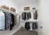 Elegant walk-in closet featuring neatly organized clothing and stylish storage baskets.