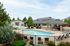 Inviting outdoor swimming pool with lounge chairs and umbrellas in a serene residential community.