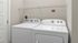 Bright and modern laundry room with a Whirlpool washer and dryer set, featuring overhead shelving.