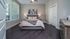 Bright and airy bedroom with a cozy gray upholstered bed, stylish artwork, and modern decor.