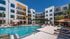 Elegant apartment complex with a sparkling outdoor pool, surrounded by lounge chairs and palm trees.