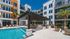 Vibrant apartment courtyard featuring a sparkling pool, modern pergola, and palm trees.