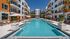 Elegant courtyard pool surrounded by modern apartment buildings with palm trees and sun loungers.