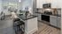 Bright open-plan living area with a modern kitchen, cozy seating, and large windows.