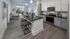 Modern kitchen with sleek cabinetry and open-plan living room featuring large windows and stylish decor.