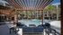 Beautiful outdoor area with modern seating, palm trees, and a sparkling swimming pool, surrounded by elegant apartment buildings.