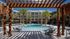 Elegant apartment complex with a beautiful pool surrounded by palm trees and lounge chairs.