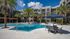 Sophisticated apartment complex with a stunning pool, palm trees, and relaxing lounge chairs under blue skies.