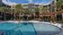 Elegant apartment courtyard with a sparkling swimming pool, surrounded by palm trees and modern architecture.
