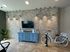 Trendy apartment interior with a brick accent wall, blue console, modern lighting, and a vintage-style bicycle.
