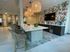 Contemporary kitchen with sleek countertops, woven bar stools, artistic wall tiles, and modern lighting.