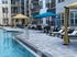 Inviting pool area with stylish loungers, cabanas, and palm trees in a modern apartment complex.