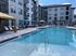 Elegant apartment complex with a crystal-clear swimming pool, poolside loungers, and stylish cabanas.