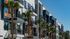 Modern apartment building with sleek balconies and palm trees in an urban setting.