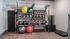 Sleek and organized home gym with a variety of exercise equipment including kettlebells, medicine balls, and resistance bands.
