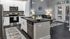 Elegant kitchen with modern appliances, island counter, and open living room with natural light.