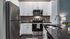 Modern kitchen with stainless steel appliances, white cabinetry, and a glossy granite countertop.
