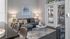 Modern living room with a stylish gray sofa, contemporary artwork, and large windows with blinds.