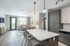 Bright and modern living room with open kitchen, featuring a large counter, stylish pendant lights, and a cozy seating area.