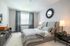 Elegant bedroom with contemporary decor, featuring a plush bed, stylish mirror, and ambient lighting.