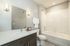 Modern bathroom featuring a pristine bathtub, elegant vanity with mirror, and ambient lighting.