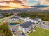 Aerial view of a modern apartment complex surrounded by lush greenery and a vibrant sunset backdrop.