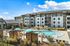 Stunning apartment complex with resort-style pool and cabanas under a bright blue sky.