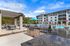 Chic outdoor area with grilling stations, a pool, and modern apartment building under a blue sky.
