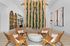 Contemporary lounge area with woven chairs, abstract art, and hanging greenery for a stylish appeal.