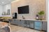 Modern kitchenette with sleek cabinetry, pebble-stone backsplash, and integrated appliances.