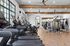 Spacious modern gym with treadmills, elliptical machines, and strength training equipment in a bright apartment complex.