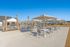 Charming outdoor patio with tables, chairs, and umbrellas under a clear blue sky.