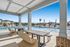 Outdoor pool with modern seating area and sun loungers under blue sky.