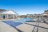 Inviting outdoor pool area with modern lounge chairs and a stylish pavilion under a clear blue sky.