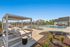 Elegant outdoor pool area with modern lounge chairs, cabana, and vibrant greenery under a bright blue sky.