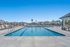 Elegant outdoor swimming pool surrounded by modern lounge chairs and palm trees under a clear blue sky.