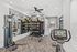 Modern fitness room with exercise equipment, mirrors, and natural lighting.