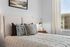 Contemporary bedroom with a plush bed, decorative pillows, and ambient lighting.