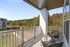 Inviting balcony with cozy seating overlooking lush greenery and a neighboring building.