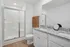 3-Bedroom Townhouses in Huntsville, AL - Elio at Research Park - Modern Bathroom With Double-Sink Vanity, Granite Countertops, Large Mirror, and Glass-Enclosed Shower.