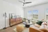 Pet-Friendly Townhouses in Huntsville, AL - Elio at Research Park - Bright Living Room With Wood-Style Plank Flooring, Leather Sofa, Round Coffee Table, Armchair, Ceiling Fan, Cabinet, and Windows.