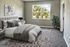 Inviting bedroom with plush carpeting, modern decor, and large window overlooking lush greenery, creating a serene retreat.