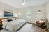Inviting bedroom with plush king-sized bed, modern artwork, sleek ceiling fan, and elegant lighting on rich wooden floors.