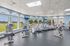 Modern fitness center with large windows offering scenic views, featuring state-of-the-art cardio machines and exercise equipment.