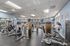 Modern fitness center with advanced exercise equipment, large windows, and bright lighting.