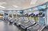 Bright and inviting fitness center with state-of-the-art treadmills, exercise bikes, and expansive windows showcasing scenic outdoor views.