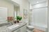 Elegant bathroom with granite countertop, modern fixtures, stylish art, and a lush green plant. Features a bathtub with a chic shower curtain and tile accents.