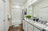 Elegant bathroom featuring dual granite sinks, stylish white cabinetry, and a sleek bathtub with modern fixtures.